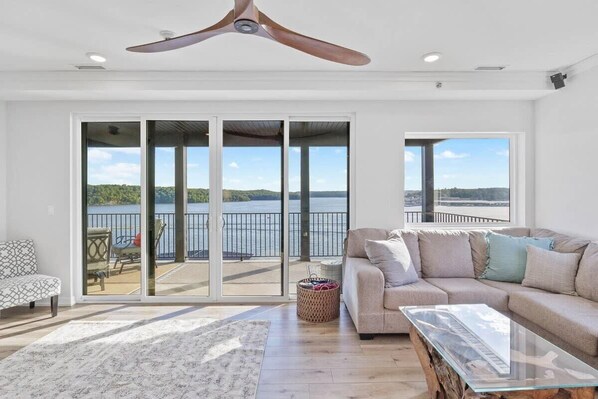 A spacious living room with a large sliding glass door leading to a balcony with a view of the water.