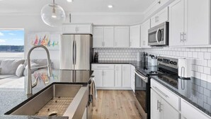 Une cuisine moderne avec des meubles blancs, des appareils en acier inoxydable et un plan de travail noir.