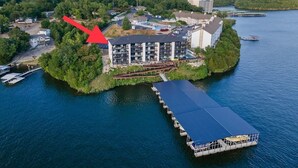 Vue aérienne d’une propriété située au bord de l’eau, avec un grand bâtiment, un quai et une jetée s’avançant dans l’eau.