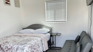 A bedroom with a bed, bedside table, and a sofa. - Comfortable Tiny House in a Great Location (Moreno Valley)