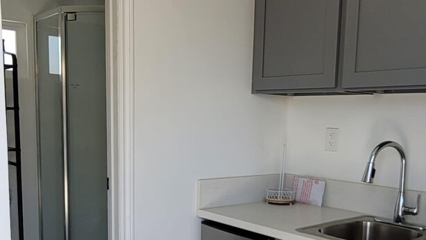 A modern kitchen with grey cabinets, stainless steel appliances, and a walk-in closet. - Comfortable Tiny House in a Great Location (Moreno Valley)