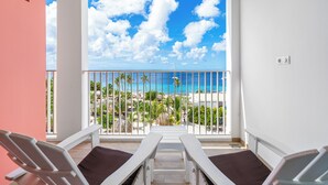 Un balcón con dos sillones blancos y vista a la playa y al océano.