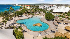 Un resort con una amplia piscina, zona de playa y vistas al océano.