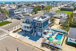 A two-story house with a balcony, a swimming pool, and a stop sign.