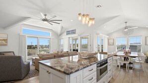 A spacious kitchen with a large island, white cabinetry, and a ceiling fan. - Awesome 5 bed, 5 bath, heated pool - short walk to the beach! (Surf City)