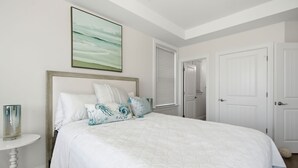 A bedroom with a bed, a bedside table, a lamp, a window with blinds, and a door. - Awesome 5 bed, 5 bath, heated pool - short walk to the beach! (Surf City)