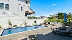 A residential swimming pool with lounge chairs and a patio area. - Awesome 5 bed, 5 bath, heated pool - short walk to the beach! (Surf City)