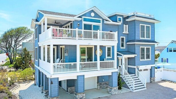 A two-story house with a balcony, a front porch, and a staircase leading to the second floor. - Awesome 5 bed, 5 bath, heated pool - short walk to the beach! (Surf City)