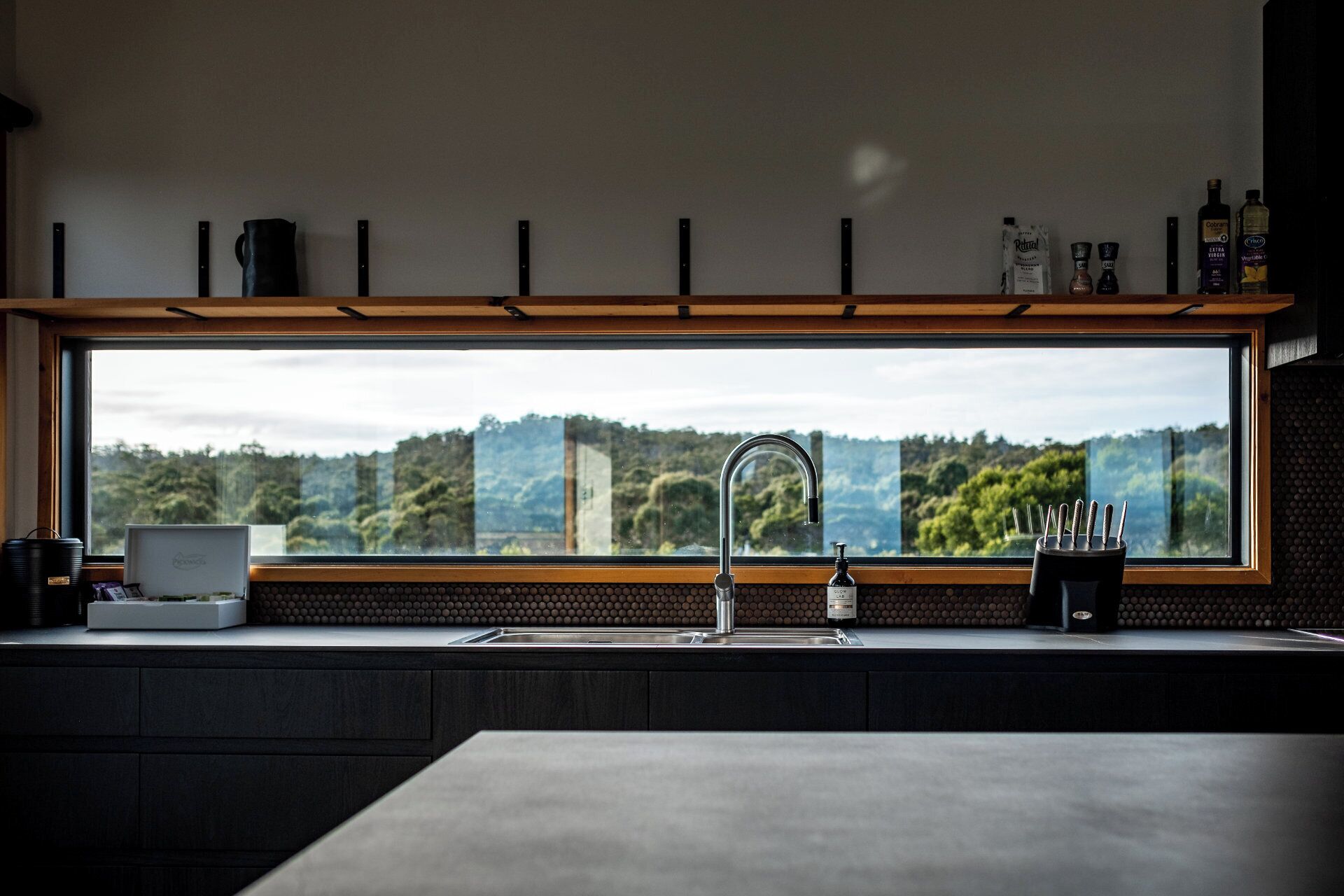 A kitchen with a large window, a sink, and a countertop with various items.