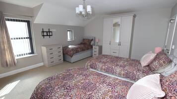 Een slaapkamer met twee bedden, een garderobe, een spiegel en een raam met gordijnen.