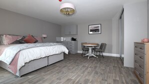 A modern bedroom with a bed, bedside table, and a small dining area with a table and chairs.