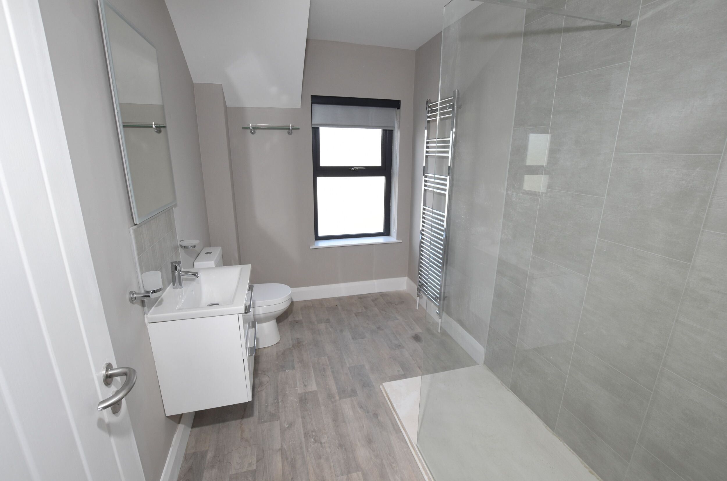 A modern bathroom with a shower, toilet, and sink.