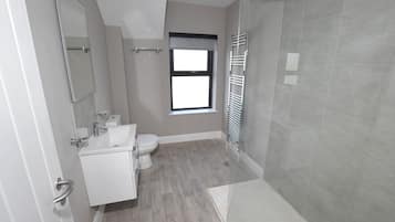 A modern bathroom with a shower, toilet, and sink.