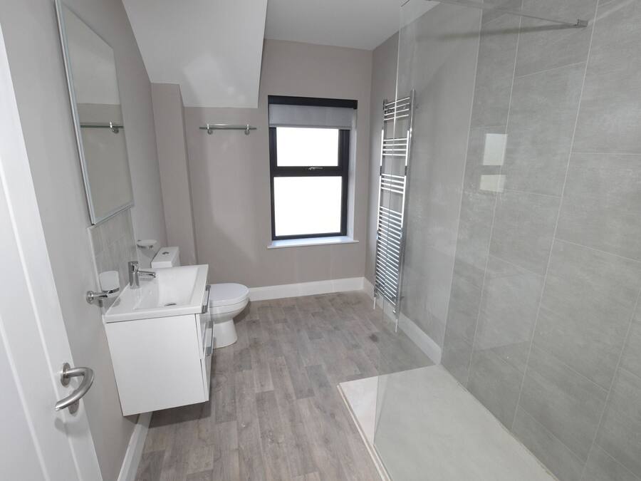 A modern bathroom with a shower, toilet, and sink.