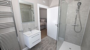 A modern bathroom with a glass shower enclosure, a white vanity, and a walk-in shower.