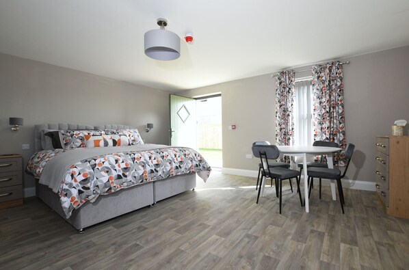 A bedroom with a bed, bedside tables, a desk, and chairs.