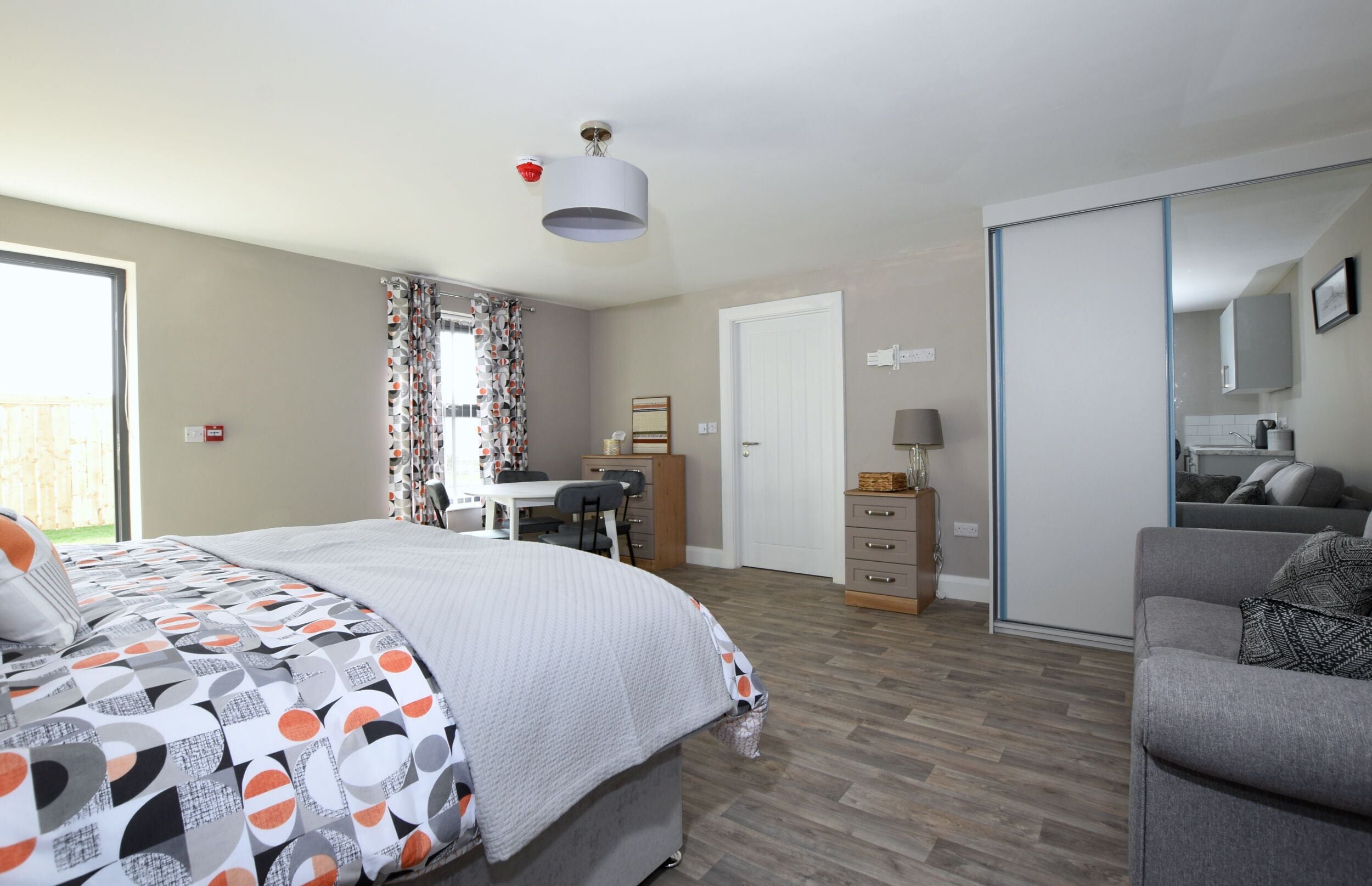 A bedroom with a bed, desk, and wardrobe.