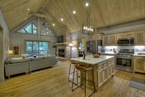 Une cuisine spacieuse avec des meubles en bois, un grand îlot central et une cheminée en pierre.