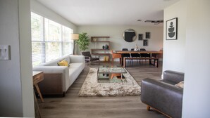 A modern living room with a sofa, a coffee table, and a dining area with chairs and a table. - ❤️ of Ormond Beach ⭐️Self check-in⭐️Beach (Ormond Beach)