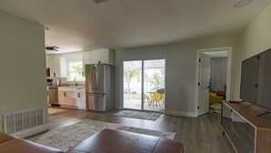 A modern kitchen with stainless steel appliances, a dining area with yellow chairs, and a large sliding glass door leading to an outdoor patio. - ❤️ of Ormond Beach ⭐️Self check-in⭐️Beach (Ormond Beach)