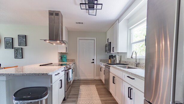 A modern kitchen with white cabinets, stainless steel appliances, and a window providing natural light. - ❤️ of Ormond Beach ⭐️Self check-in⭐️Beach (Ormond Beach)