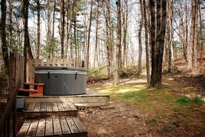 A hot tub in a forested area with a wooden deck and a picnic table. - Lazy Lane Cabins - Pleasant View (Logan)