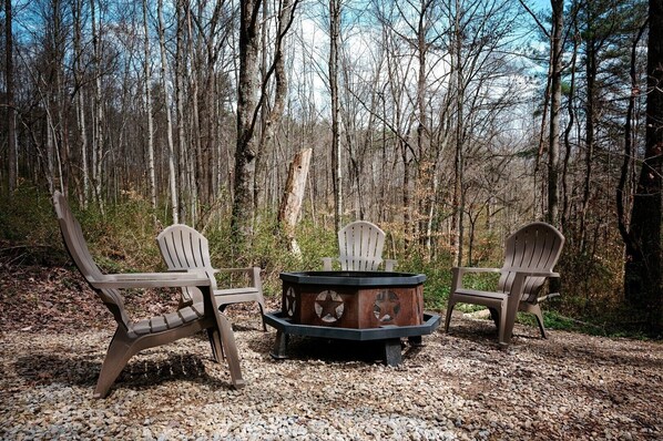 Un décor forestier avec un foyer et des fauteuils Adirondack.