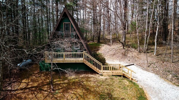 Une cabane dotée d’une terrasse en bois et d’un escalier menant à une entrée surmontée d’un toit végétalisé.