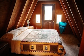 A bedroom with a bed, a nightstand, a window, and a door.