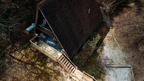 Vue aérienne d’une maison avec un toit en pente, une terrasse en bois et un chemin de gravier.