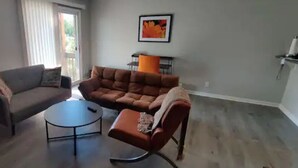 A living room with a sofa, armchair, and coffee table. - Cozy contemporary 1-bedroom condo with fireplace (Aurora)