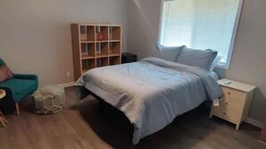 A bedroom with a bed, a chair, a small table, a bookshelf, and a window. - Cozy contemporary 1-bedroom condo with fireplace (Aurora)