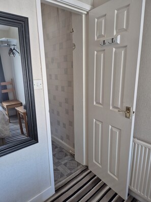 A hallway with a white door, a mirror, and a tiled wall. - The Rutlands (Blackpool)