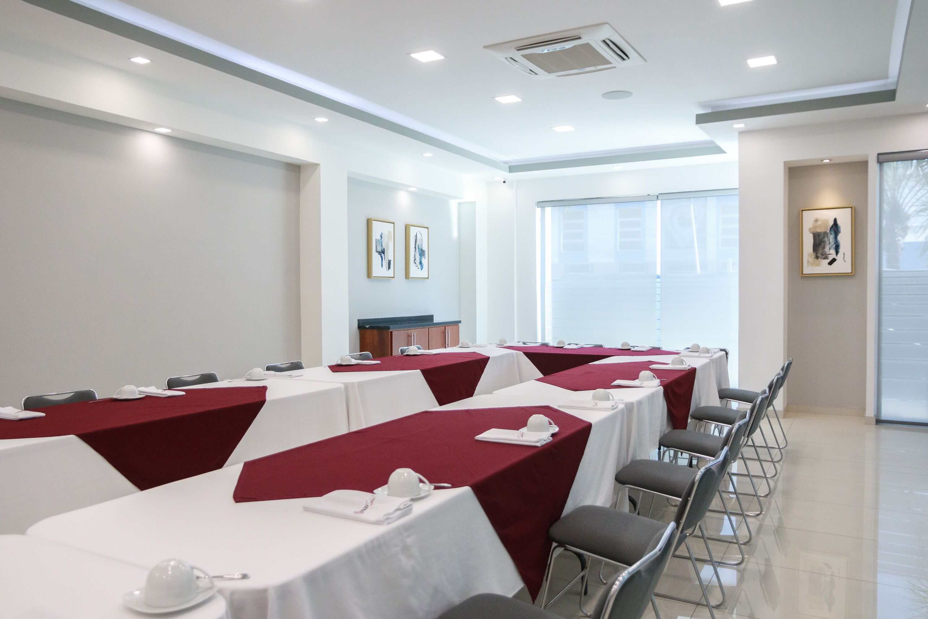 Un salón de conferencias con mesas dispuestas para reuniones, equipado con tarjetas de identificación y vasos de agua.