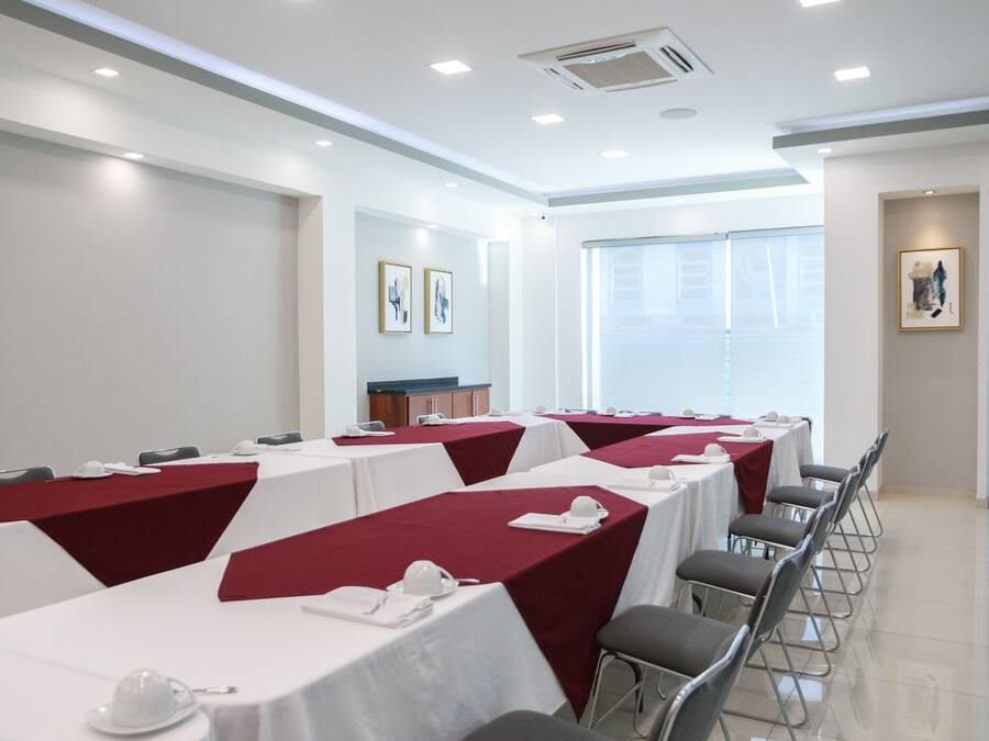 Un salón de conferencias con mesas dispuestas para reuniones, equipado con tarjetas de identificación y vasos de agua.