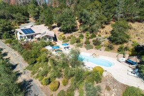 Una casa con piscina, rodeada de jardines y árboles cuidadosamente diseñados.