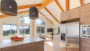 A modern kitchen with wooden cabinetry, a stainless steel refrigerator, and pendant lighting. - Trinity - Secluded Retreat - Pool, Hot Tub, Bocce (Glen Ellen)