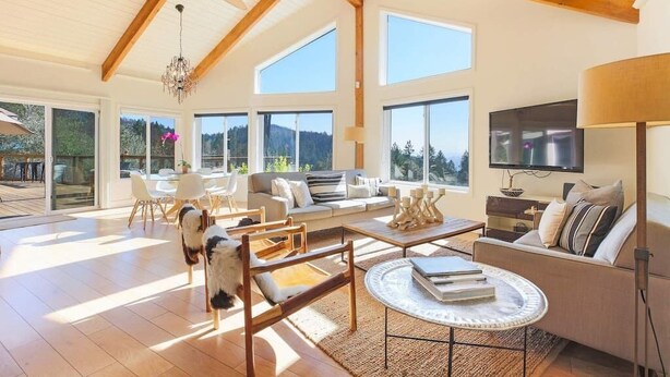 A spacious living room with a high ceiling, large windows, a ceiling fan, and a television. - Trinity - Secluded Retreat - Pool, Hot Tub, Bocce (Glen Ellen)
