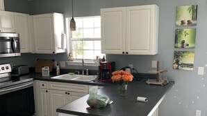 A kitchen with white cabinets, a black countertop, a stainless steel oven, a microwave, a sink, and a window. - Casa Tranquilo    Heated Pool and Sauna (Gulf Breeze)