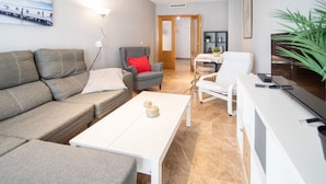 Un salon moderne avec un canapé gris, une table basse blanche, un fauteuil gris et une table à manger blanche.