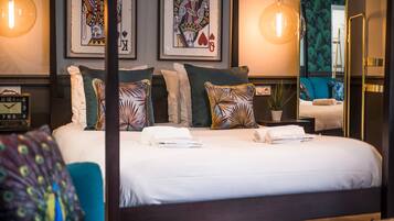 A neatly made bed with white linens, multiple pillows, and a bedside table with a lamp.