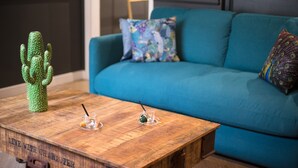 A wooden coffee table with a cactus, two glasses with straws, and a decorative item. A teal sofa with patterned pillows is in the background. - The Royal Elysée Suite (Paris)