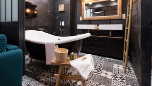 A modern bathroom with a freestanding bathtub, a wooden vanity, and a large mirror. - The Royal Elysée Suite (Paris)