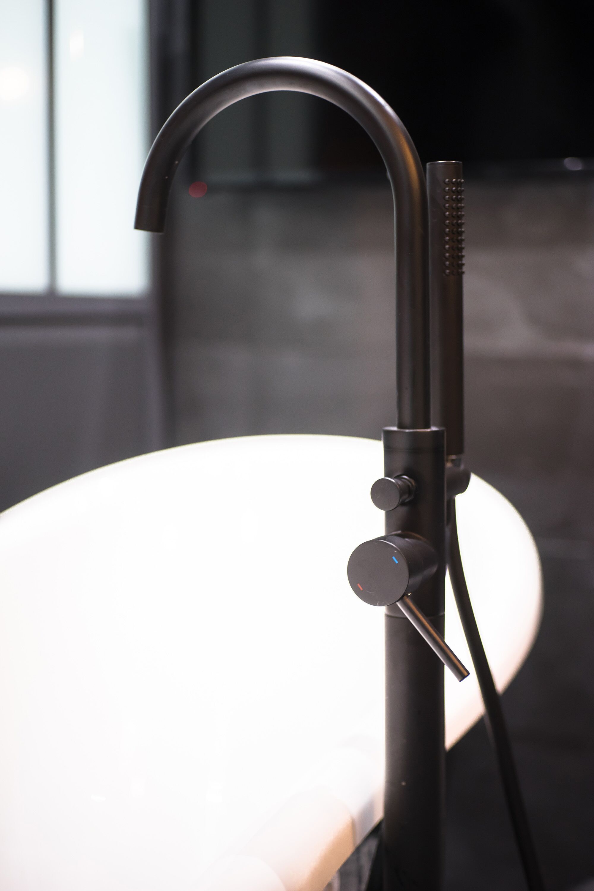 A modern bathroom with a sleek, black faucet mounted on a white countertop.