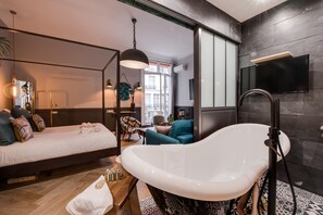 Une chambre à coucher moderne avec un grand lit, une baignoire et un téléviseur fixé au mur.