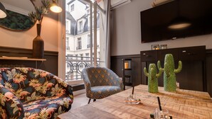 A modern living room with a sofa, armchair, and cactus sculptures on a wooden table. - The Royal Elysée Suite (Paris)