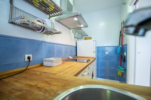 A kitchen with blue tiles, a wooden countertop, a stainless steel sink, and a white refrigerator. - The Rose Studio in Cadiz (Cádiz)