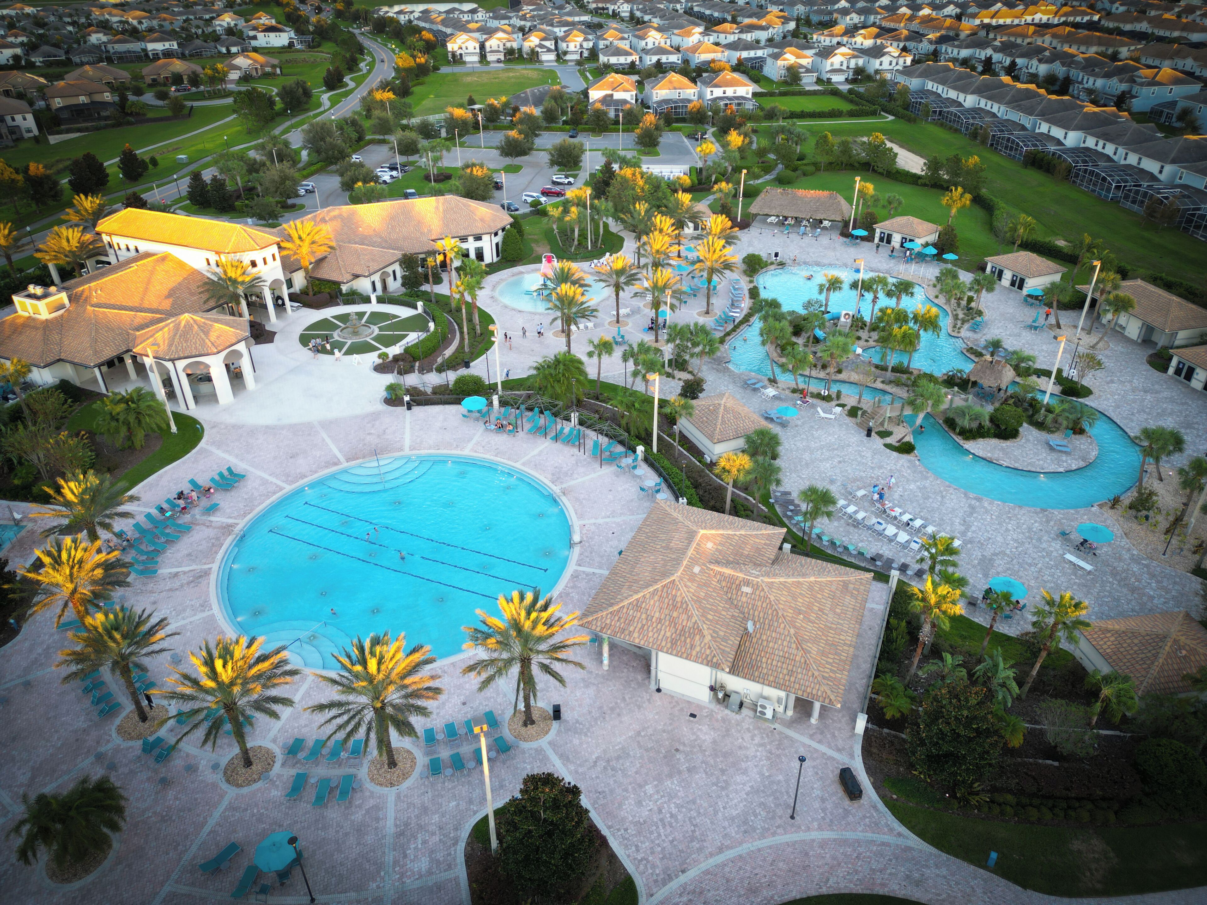 Luchtbeeld van een resort met meerdere zwembaden, palmbomen en een verzorgd landschap.