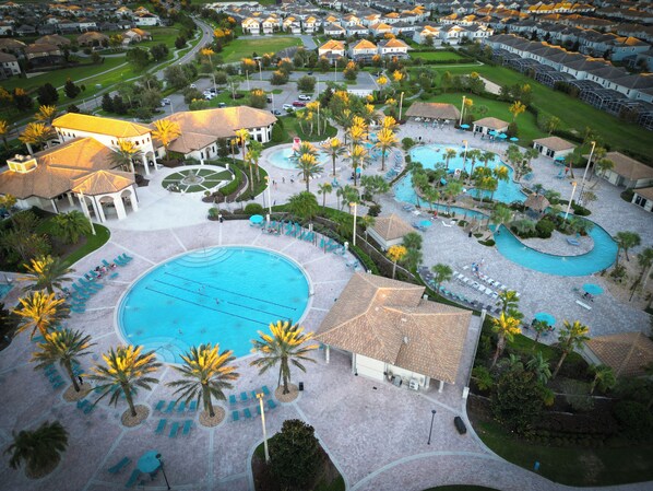 An aerial view of a resort with multiple swimming pools, palm trees, and a well-maintained landscape.