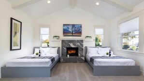 A modern bedroom with two beds, a fireplace, and large windows. - Full House ➡️ Hut Tub (Aloha)